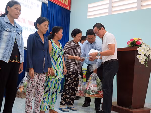 Ông Lâm Tấn Lợi trao quà và chụp hình lưu niệm với những gia đình có hoàn cảnh khó khăn.