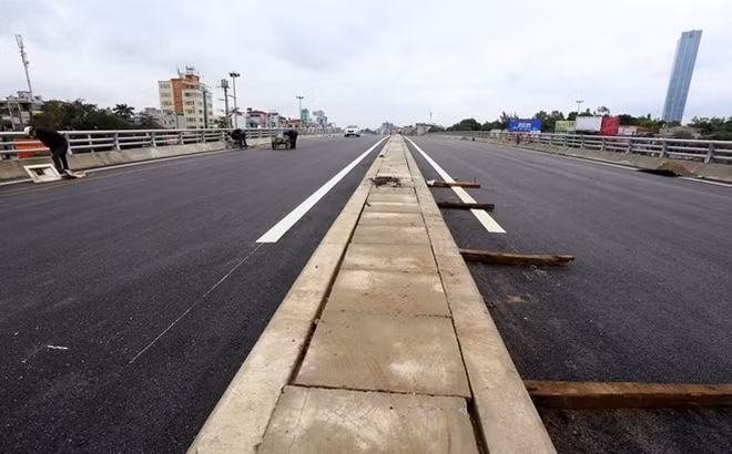 Mặt cầu vượt nút Cầu Giấy đã được thảm nhựa, hệ thống thoát nước đã làm xong. Công nhân đang gấp rút lắp đặt hệ thống đèn điện chiếu sáng.