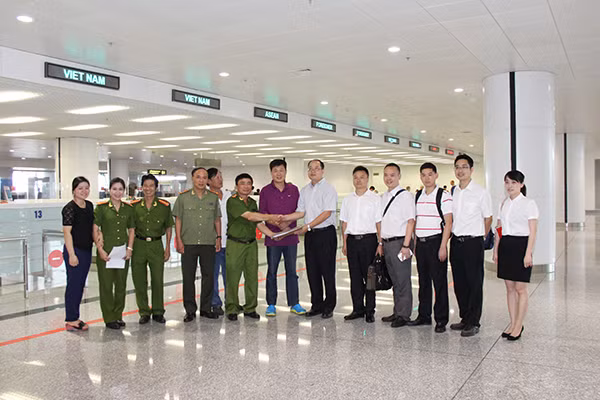 Cảnh sát Việt Nam bàn giao hồ sơ và đối tượng truy nã quốc tế (đối tượng mặc áo tím) cho Cảnh sát Trung Quốc tại sân bay quốc tế Nội Bài.