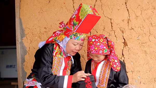 Các em nhỏ đang được chị Lý Thị Hạnh và mẹ dạy thêu.