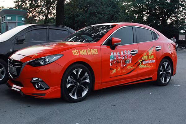 Mazda6 màu đỏ dán biểu ngữ và hình ảnh đội tuyển Việt Nam.