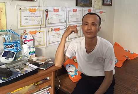Anh Mai Anh Tuấn bên những giấy khen của con trai và của anh trong căn phòng trọ.