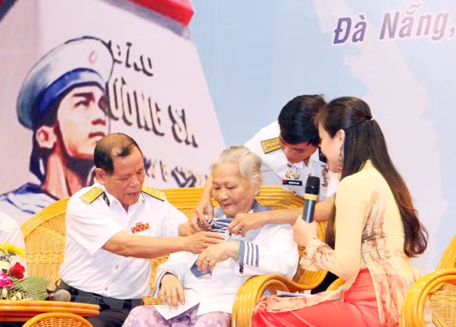 Bà Lê Thị Muộn, mẹ của Liệt sỹ Phan Văn Sự, người đã hy sinh anh dũng trong trận chiến bảo vệ chủ quyền biển đảo Tổ quốc ở Gạc Ma năm 1988, mặc chiếc áo - kỷ vật duy nhất còn lại của người con trai, tại chương trình giao lưu Hướng về Trường Sa thân yêu, ngày 14/3/2013. (Ảnh: Trần Lê Lâm/TTXVN)