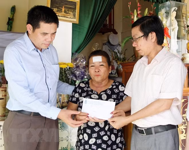 Đại diện Liên đoàn Lao động tỉnh Quảng Trị và Quỹ từ thiện xã hội Tấm lòng Vàng (Báo Lao động) trao tiền hỗ trợ cho bà Nguyễn Thị Hằng, trú tại thành phố Đông Hà, tỉnh Quảng Trị, là mẹ liệt sĩ Hoàng Ánh Đông hy sinh trong cuộc chiến đấu bảo vệ chủ quyền biển đảo Tổ quốc ở Gạc Ma năm 1988. (Ảnh: Hồ Cầu/TTXVN)