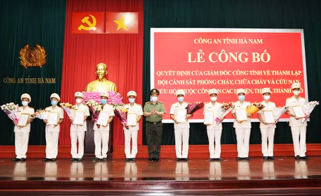 Đại tá Nguyễn Quốc Hùng, Giám đốc Công an tỉnh Hà Nam trao Quyết định và tặng hoa chúc mừng các đồng chí thuộc Đội Cảnh sát PCCC&CNCH Công an các huyện, thị xã, thành phố.