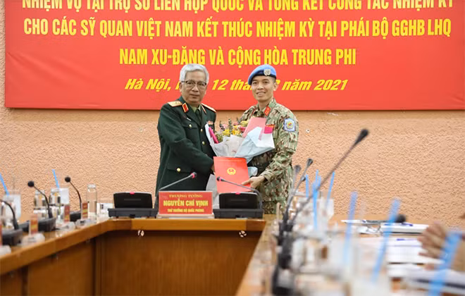 Thừa ủy quyền của Chủ tịch nước, Thượng tướng Nguyễn Chí Vịnh trao quyết định và tặng hoa chúc mừng Trung tá Trần Đức Hưởng.