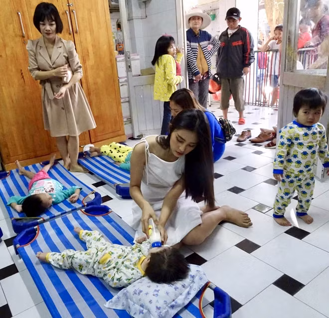 Người đẹp ân cần cho trẻ khuyết tật uống sữa