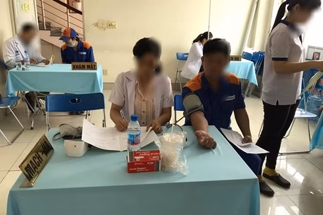 Bà N. ngồi vào bàn đo huyết áp cho người lao động (ảnh Đ.T)