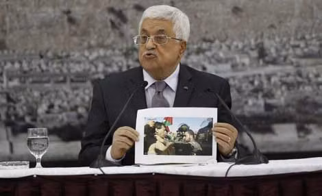 Tổng thống Palestine Mahmoud Abbas lên án vụ gây ra cái chết của Bộ trưởng Abu Ein (trên tay ông cầm tấm ảnh vụ xô xát với binh lính Israel). Ảnh: Reuters.