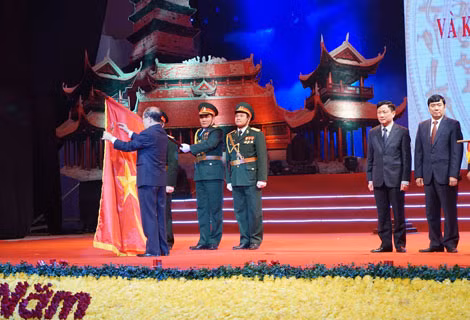 Chủ tịch Quốc hội Nguyễn Sinh Hùng gắn Huân chương Độc lập hạng Nhất lên lá cờ truyền thống của tỉnh Vĩnh.