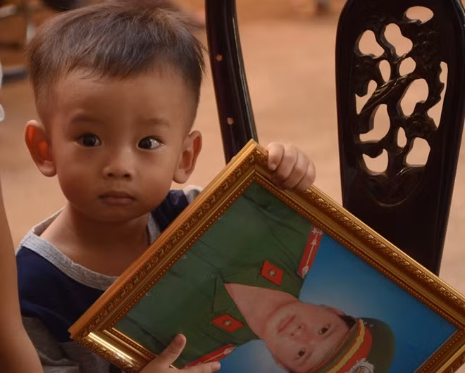 Hình ảnh cậu con trai 2 tuổi ngơ ngác cầm di ảnh Đại úy Long khiến ai nhìn thấy cũng quặng lòng