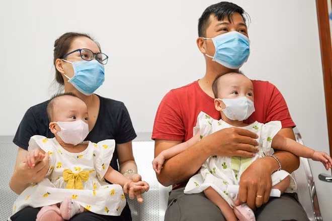 Hai bé đeo khẩu trang đi tiêm phòng