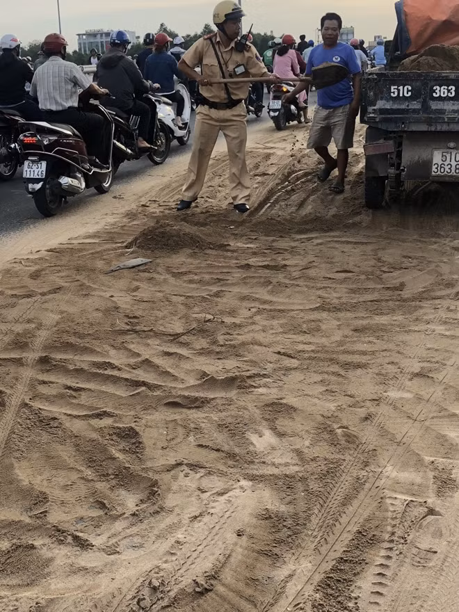 Chiến sĩ Cảnh sát giao thông cùng người dân sinh sống hai bên đường tổ chức khắc phục, dọn dẹp đất cát rơi vãi trên mặt đường.