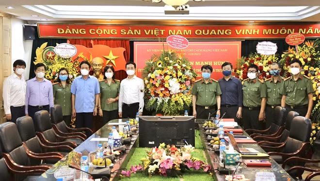 Bộ trưởng Bộ Thông tin và Truyền thông Nguyễn Mạnh Hùng trao lẵng hoa chúc mừng Báo CAND.