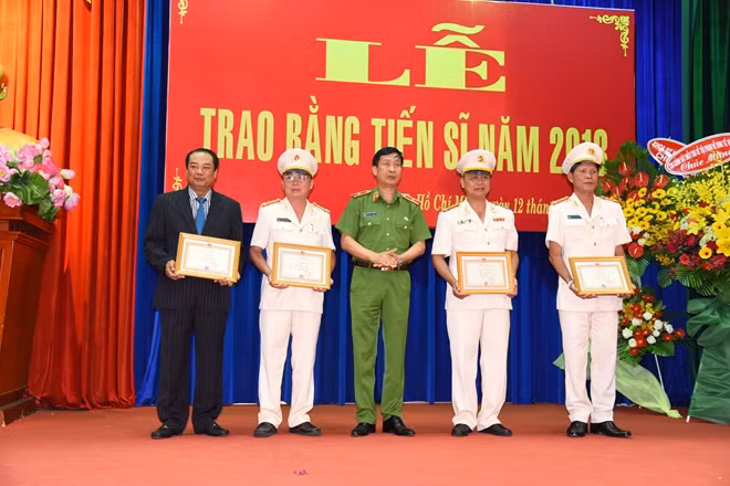 Thiếu tướng GS.TS Nguyễn Văn Nhật lên trao Giấy khen cho 4 tân tiến sĩ có thành tích xuất sắc trong thời gian học tập và làm nghiên cứu sinh.