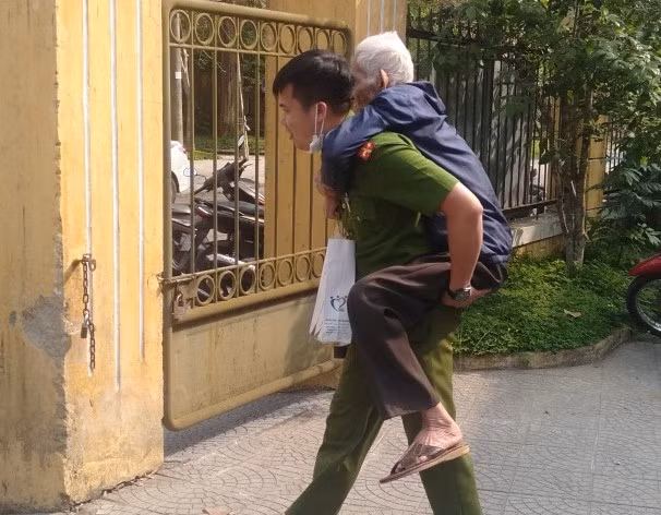 Trung úy Trần Văn Cói, cán bộ Công an phường Tây Lộc, TP Huế cõng cụ già đi làm CCCD.