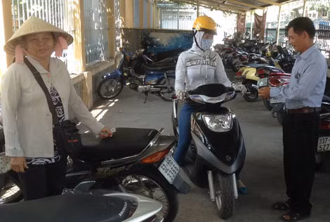 Trung úy Nguyễn Đức Thọ (bìa phải) cùng vợ trông giữ xe tại trụ sở ủy ban phường.