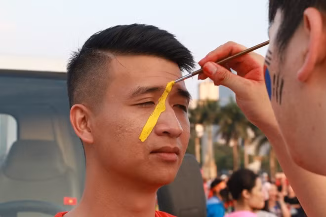 Nhiều CĐV khác tranh thủ thời gian trước trận đấu để vẽ cờ tổ quốc lên mặt.