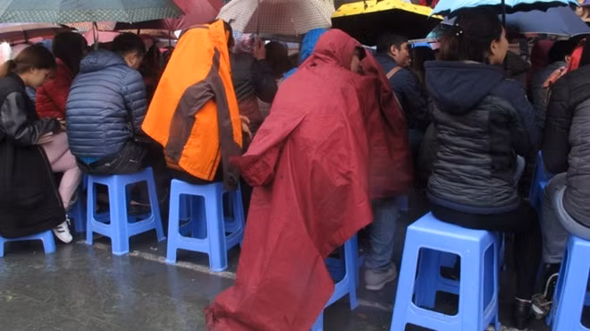Do mưa ngày càng nặng hạt nên nhiều người phải mặc cả áo mưa để chờ đến lượt mua vàng.