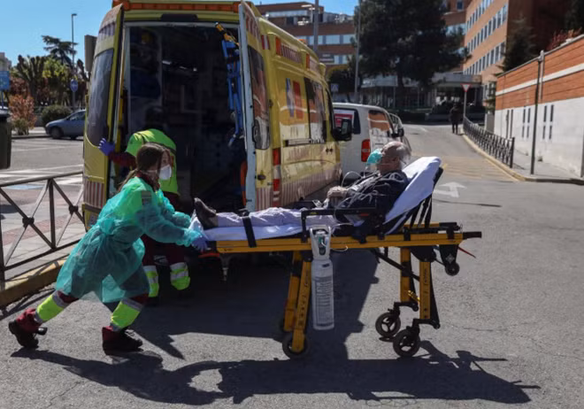 Nhân viên y tế Tây Ban Nha vận chuyển bệnh nhân nhiễm COVID-19 tại Madrid. Ảnh: Reuters