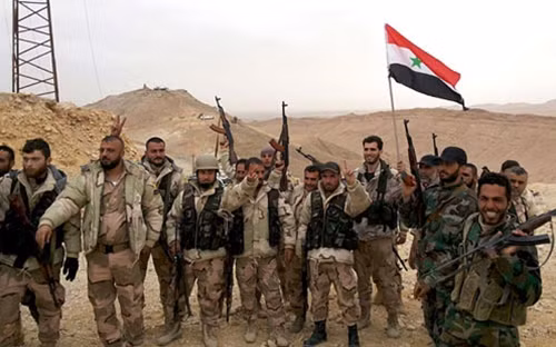 Quân đội chính phủ Syria và lực lượng đồng minh giương cao lá cờ Syria sau khi giành được quyền kiểm soát thành phố cổ Palmyra. Ảnh: Reuters.