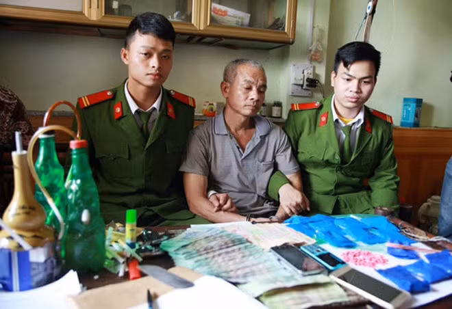 Lưu Văn Hợp (ngồi giữa) và tang vật vụ án.