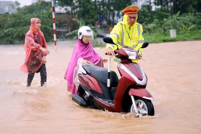 Lực lượng Cảnh sát giao thông giúp nhân dân đi lại an toàn trong vùng mưa lũ ngập lụt.