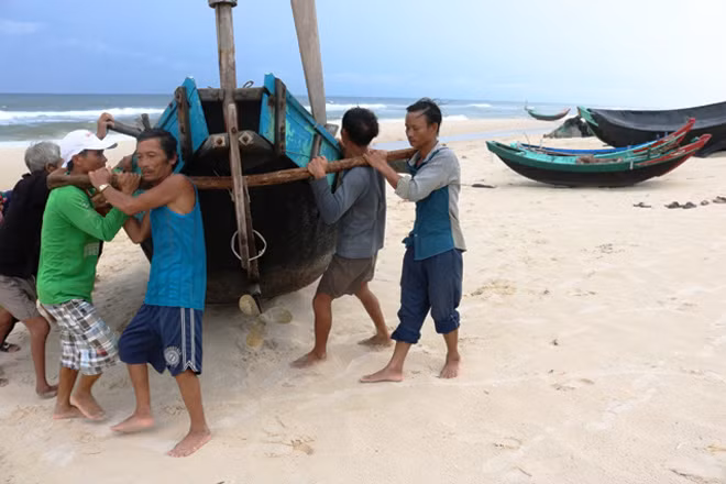 Tay trong tay, vai sát vai bà con ngư dân cố gắng đưa tàu thuyền lên càng xa bờ biển càng tốt để tránh sóng, bão “cướp” mất tàu.