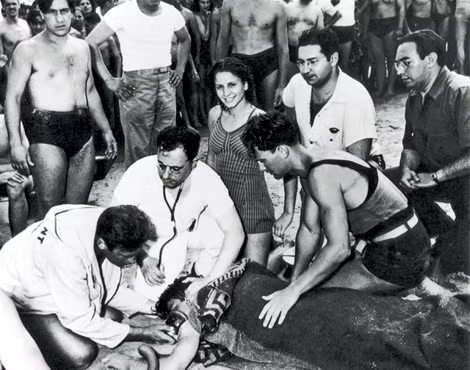 Weegee chụp bức ảnh này trên bãi biển ở đảo Coney. Cô gái đã chọn thời điểm không thích hợp để cười bên cạnh người bạn trai đang nguy kịch do đuối nước.