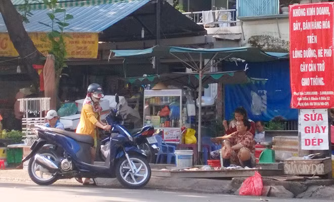 Chiếm trọn vỉa hè để buôn bán mưu sinh ngay tại nơi treo băng rôn cảnh báo mức xử phạt chiếm dụng vỉa hè.