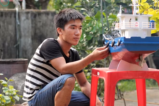 Ngư dân Trần Quốc Bình bên con tàu vỏ thép mô hình của mình.