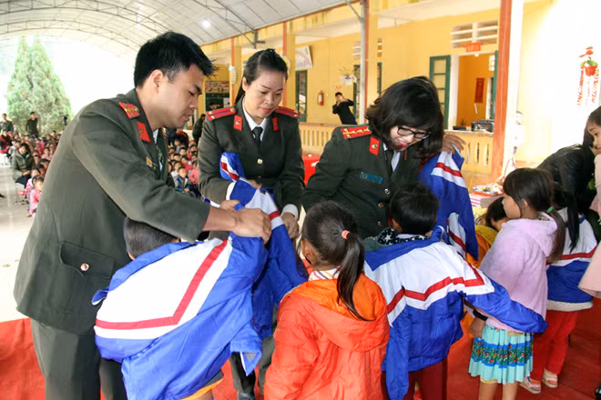 Cán bộ chiến sĩ trao áo ấm cho các học sinh.