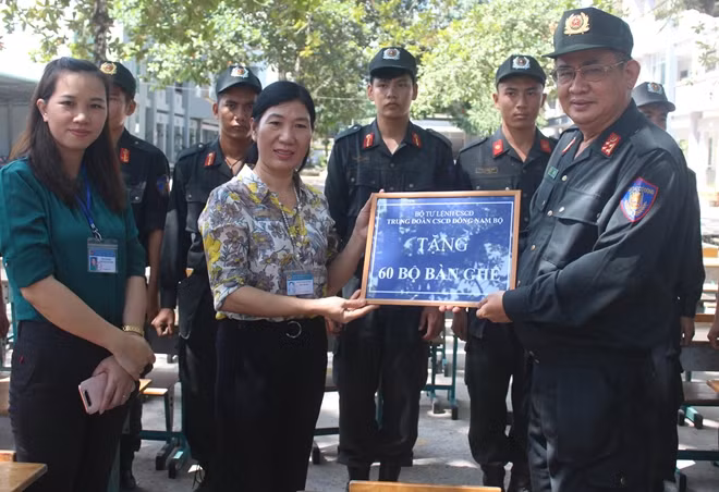Đại tá Nguyễn Xuân Mạo, Trung Đoàn trưởng Trung đoàn CSCĐ Đông Nam bộ trao tặng bàn ghế học sinh cho đại diện nhà trường.