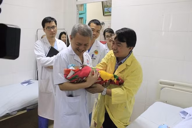 GS Lê Ngọc Thành và ê kíp bác sĩ trao cháu bé cho gia đình sản phụ.