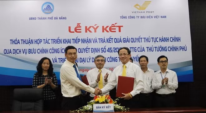 Phó Chủ tịch UBND thành phố Hồ Kỳ Minh (trái) và ông Phạm Anh Tuấn – Tổng Giám đốc VNPOST trao đổi văn bản hợp tác vừa được ký kết.