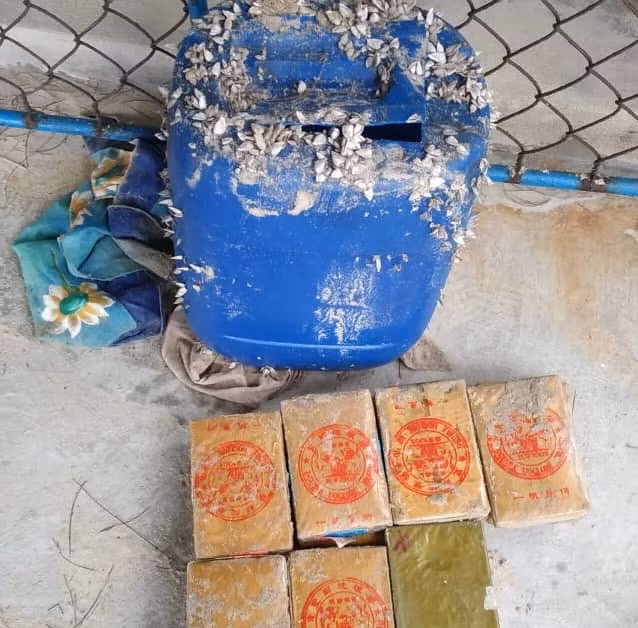 Chiếc can nhựa màu xanh và nhiều bánh ma túy có chữ Trung Quốc.