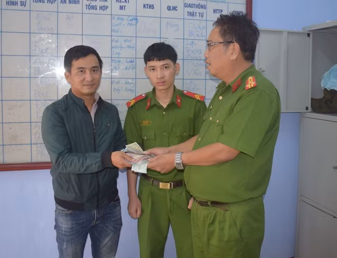 Binh nhất Lê Quang Toản (đứng giữa) nhặt tài sản đánh rơi trao trả cho anh Ngô Đức Huy (góc trái).
