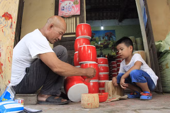 Ông Vũ Văn Hởi đang sơn trống, chờ khô để vẽ hoa văn trước khi giao hàng.