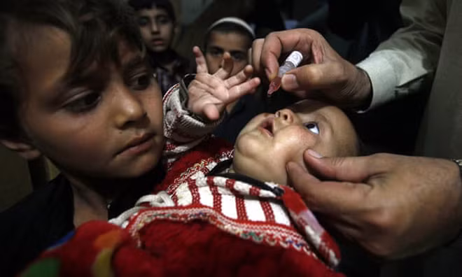 Một nhân viên y tế người Pakistan đang chăm sóc cho trẻ em ở Peshawar. Ảnh: Muhammad Sajjad/AP.