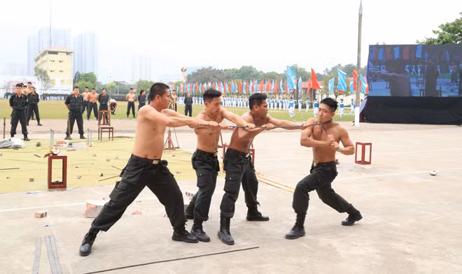 Nam CSÐN thực hiện động tác quấn thanh sắt phi 12 quanh cổ. Nam CSÐN thực hiện động tác quấn thanh sắt phi 12 quanh cổ.