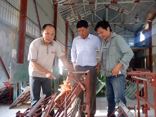 Anh Nghĩa (trái) bên máy cấy đang hoàn thiện.