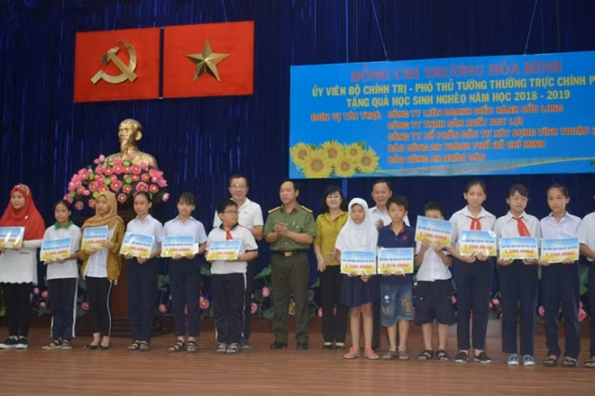 Đại diện Báo CAND và ông Lâm Tấn Lợi, Giám đốc Công ty TNHH sản xuất Duy Lợi trao tặng học bổng cho học sinh dân tộc Chăm quận 8, TP Hồ Chí Minh.