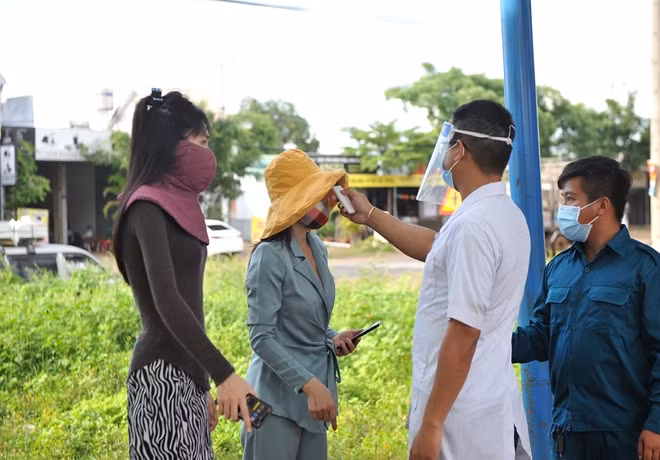 Nhân viên y tế kiểm tra thân nhiệt những người trở về từ vùng dịch tại chốt kiểm dịch liên ngành