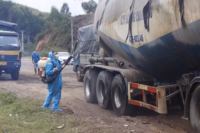 Nhân viên y tế tiến hành phun khử khuẩn phương tiện qua lại trên QL26 khi qua chốt kiểm dịch