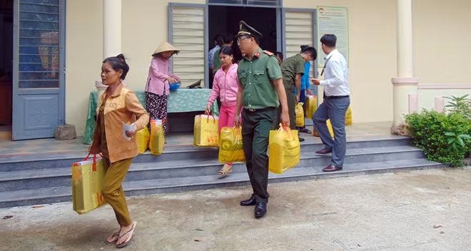 Cán bộ chiến sĩ Công an giúp người dân mang quà về nhà.