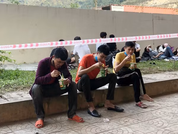 Người dân tranh thủ lót dạ những gói mì tôm mà lực lượng Công an Quảng Bình cấp phát miễn phí sau khi làm thủ tục nhập cảnh vào Việt Nam