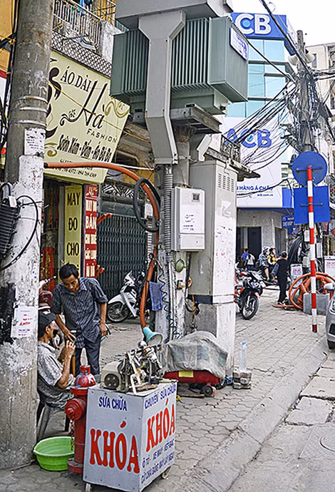 Hai người đàn ông sửa khóa dưới chân trạm biến áp Khâm Thiên 4 (quận Đống Đa). Họ cho biết đã quen làm việc và sinh hoạt tại đây nhiều năm nên không thấy nguy hiểm. Dọc tuyến đường này có đến 10 trạm biến áp.