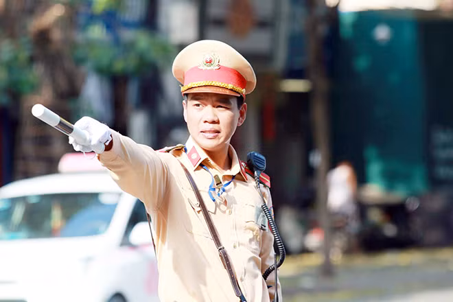 Hơi nóng rát mặt từ mặt đất bốc lên cùng với ánh nắng gắt của mặt trời khiến chiến sĩ CSGT phải nheo mắt để điều tiết giao thông trên đường.