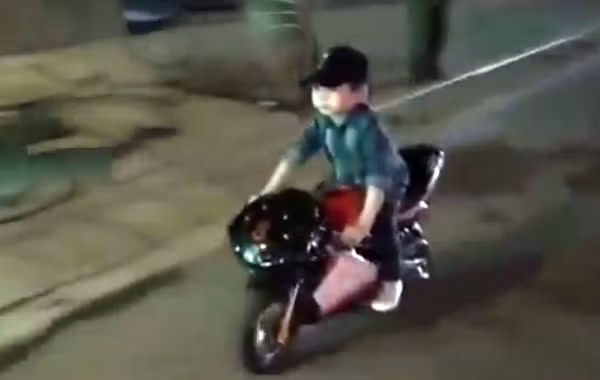 Bé trai chạy mô tô ruồi trên đường phố Hà Nội.