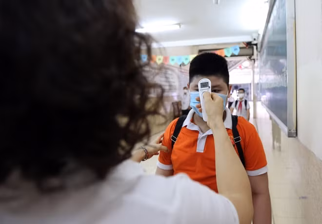 Các em học sinh trước khi vào lớp được đo thân nhiệt ngay cổng trường.